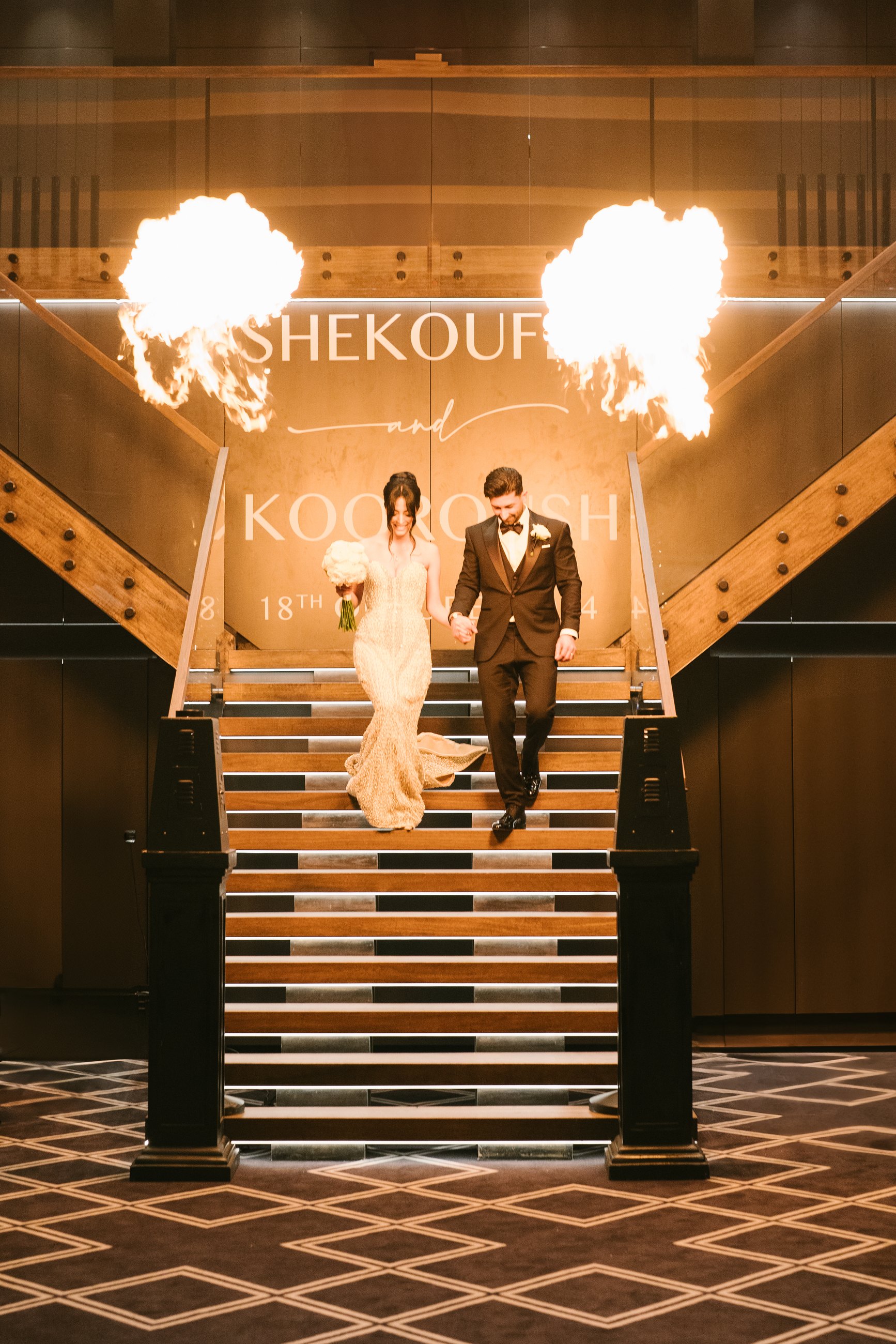 Lakeside Receptions wedding — bride and groom descending the staircase between flame jets, Taylors Lakes, photographed by C2 Films