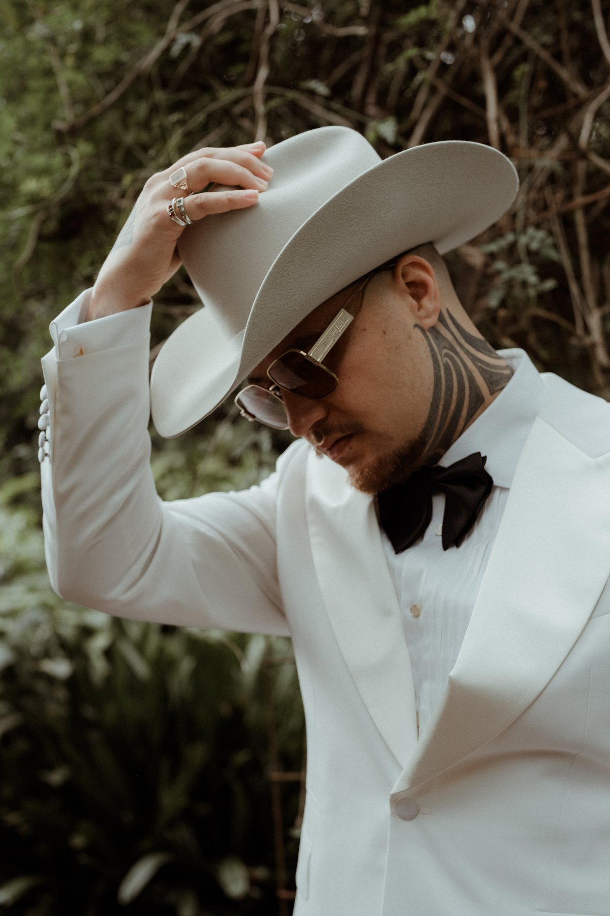 Kaleb fastening his cufflinks in a white tuxedo before the ceremony at Rosewood Estate, Beechmont QLD — wedding photography by C2 Films