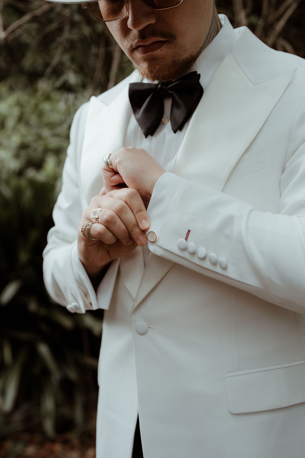 Kaleb buttoning his white dinner jacket in the hinterland light at Rosewood Estate, Beechmont QLD — wedding photography by C2 Films