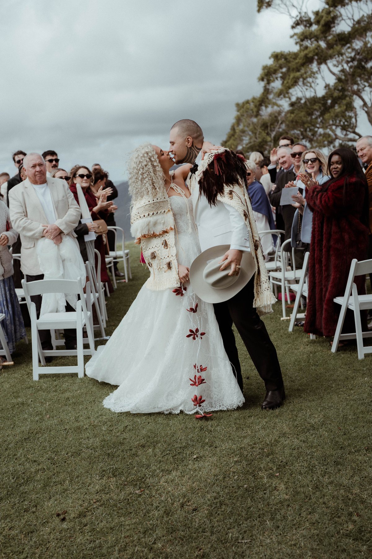 Kaleb and Monique kissing as guests applaud at Rosewood Estate, Beechmont QLD — wedding photography by C2 Films