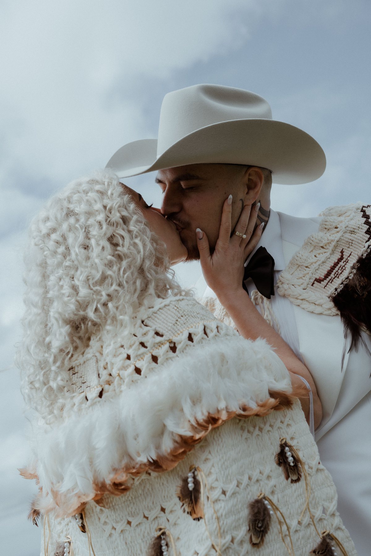 Kaleb and Monique kissing beneath the brim of his hat at Rosewood Estate, Beechmont QLD — wedding photography by C2 Films